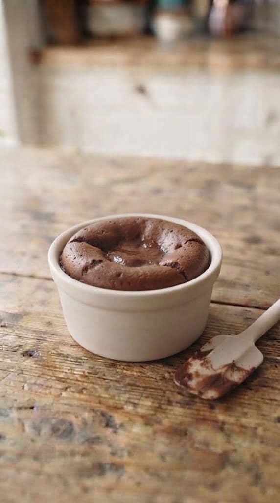 Freshly baked chocolate lava cake in a small ramekin with set edges and a soft center
