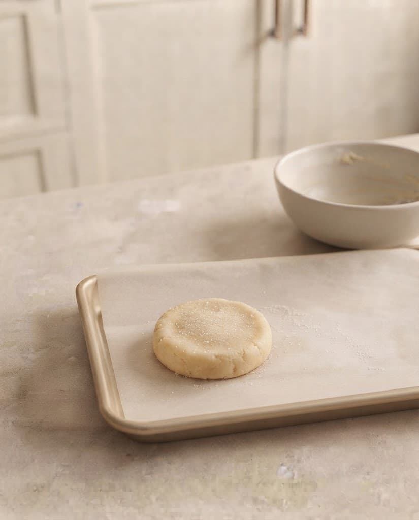 One thick raw sugar cookie shaped on parchment paper and lightly sprinkled with granulated sugar