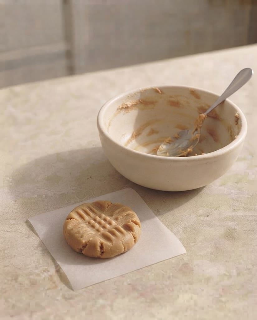 One thick peanut butter cookie dough round on parchment paper with a criss-cross fork pattern on top